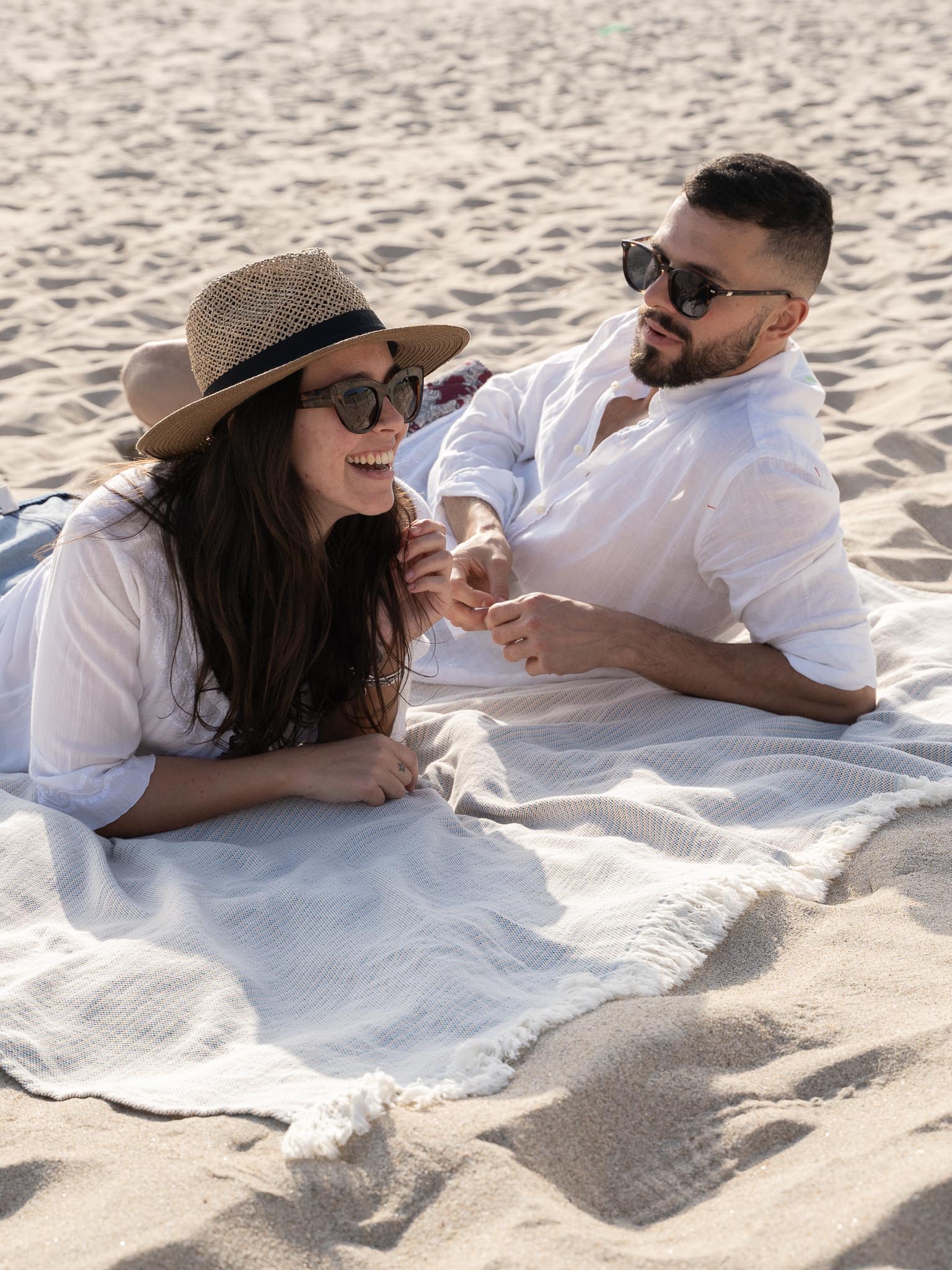 couple laying on a large blue, red and yellow beach towel