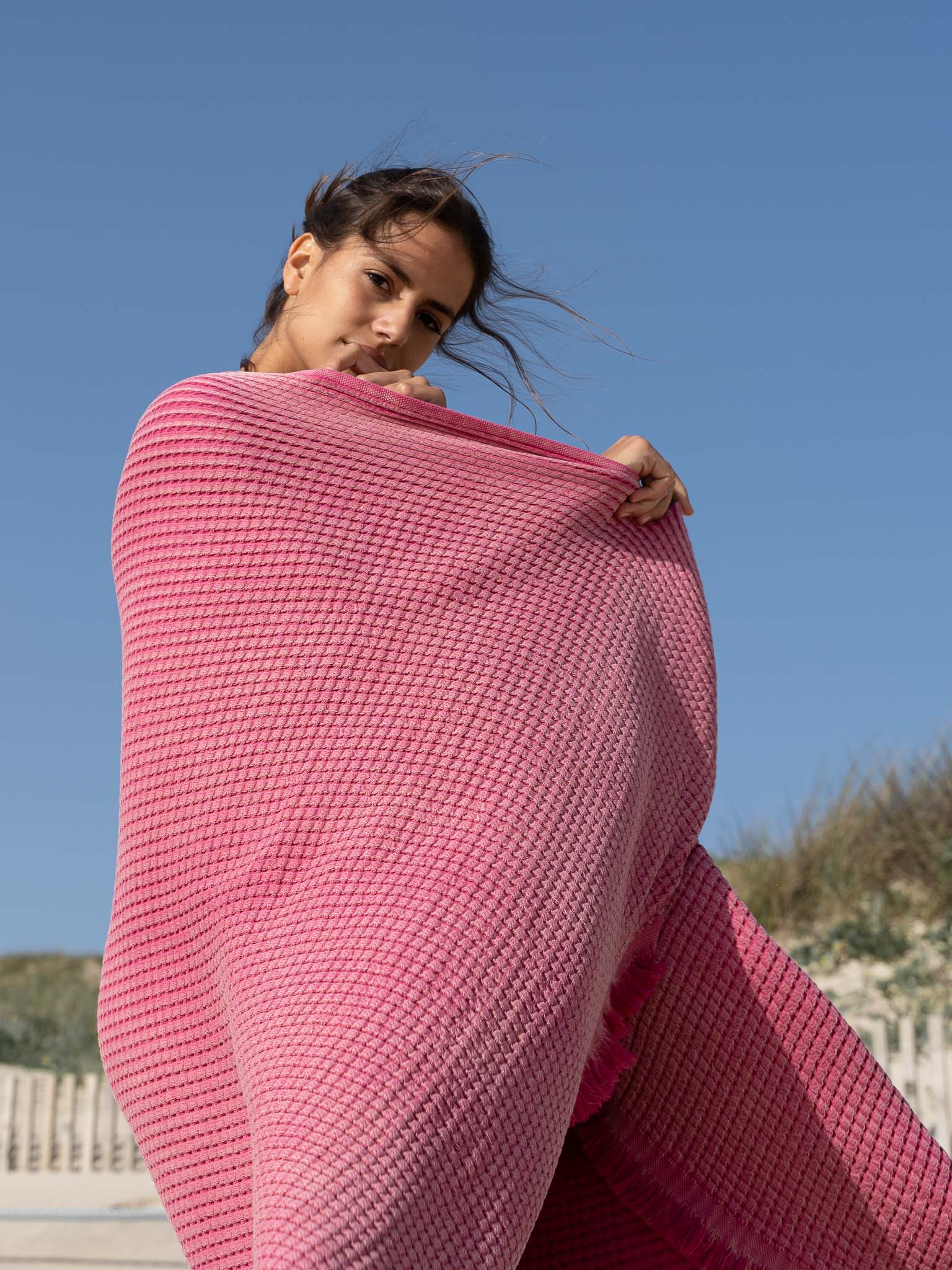 Girl on the beach with Pink double sided, honeycomb beach towel
